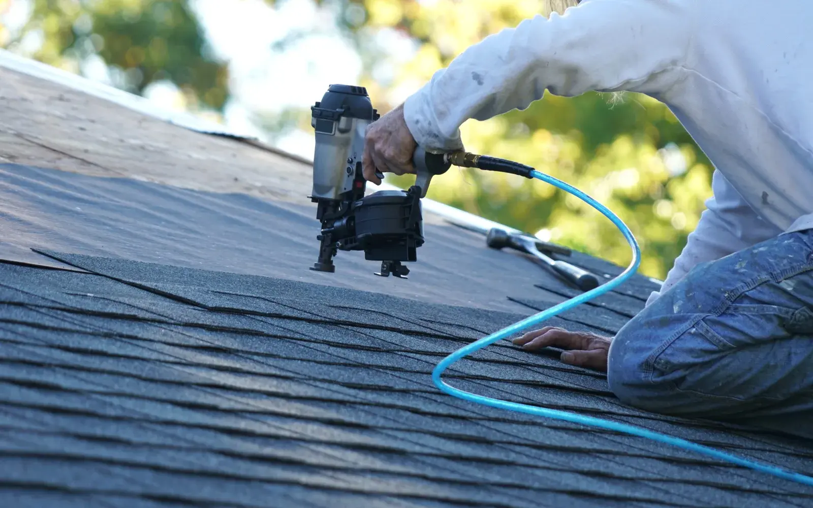 Orange Exteriors roofer fastening new asphalt shingles on a home in Eden Prairie, MN