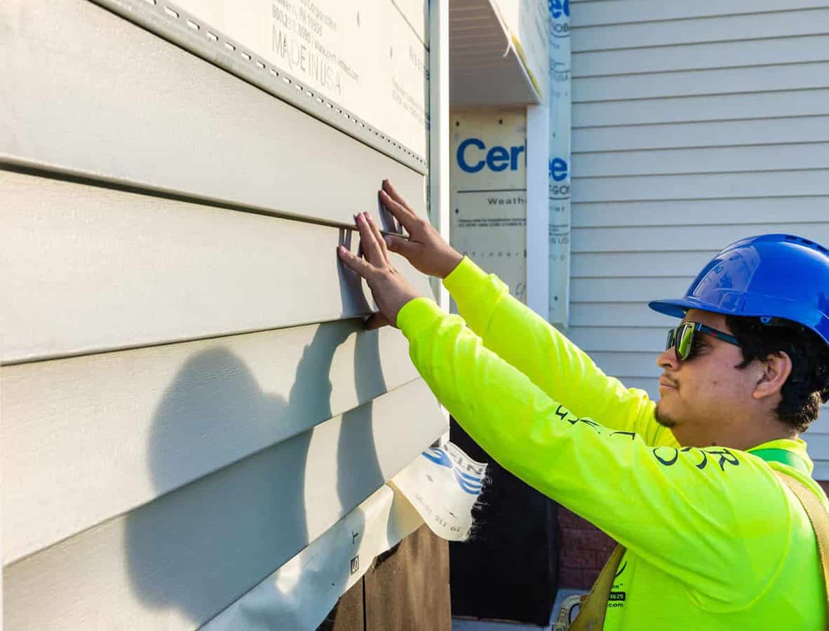 Experienced siding crew installing precision-fit exterior panels with professional tools and technique