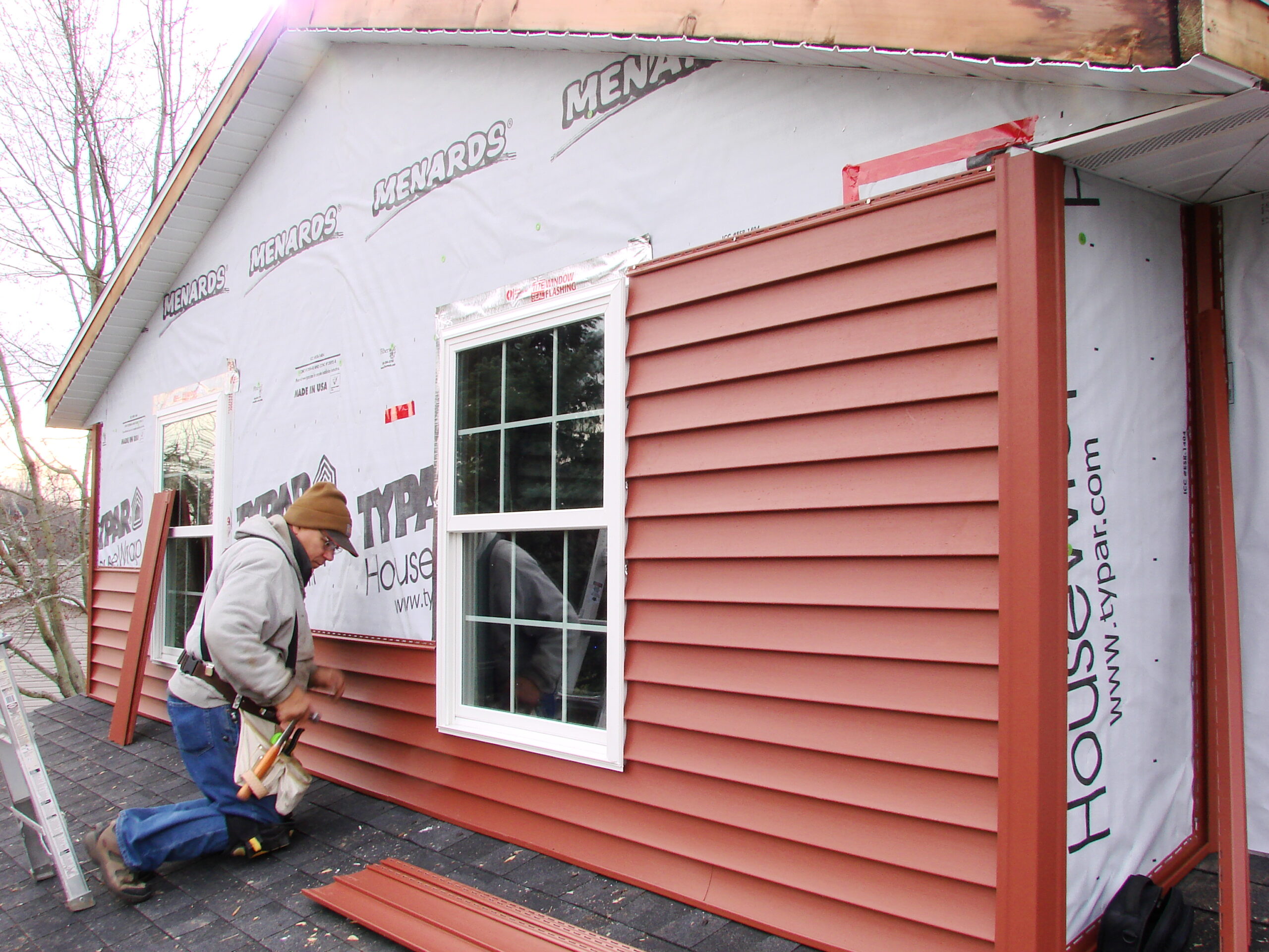Contractor repairing cracked house siding on Minnesota home after weather-related exterior damage