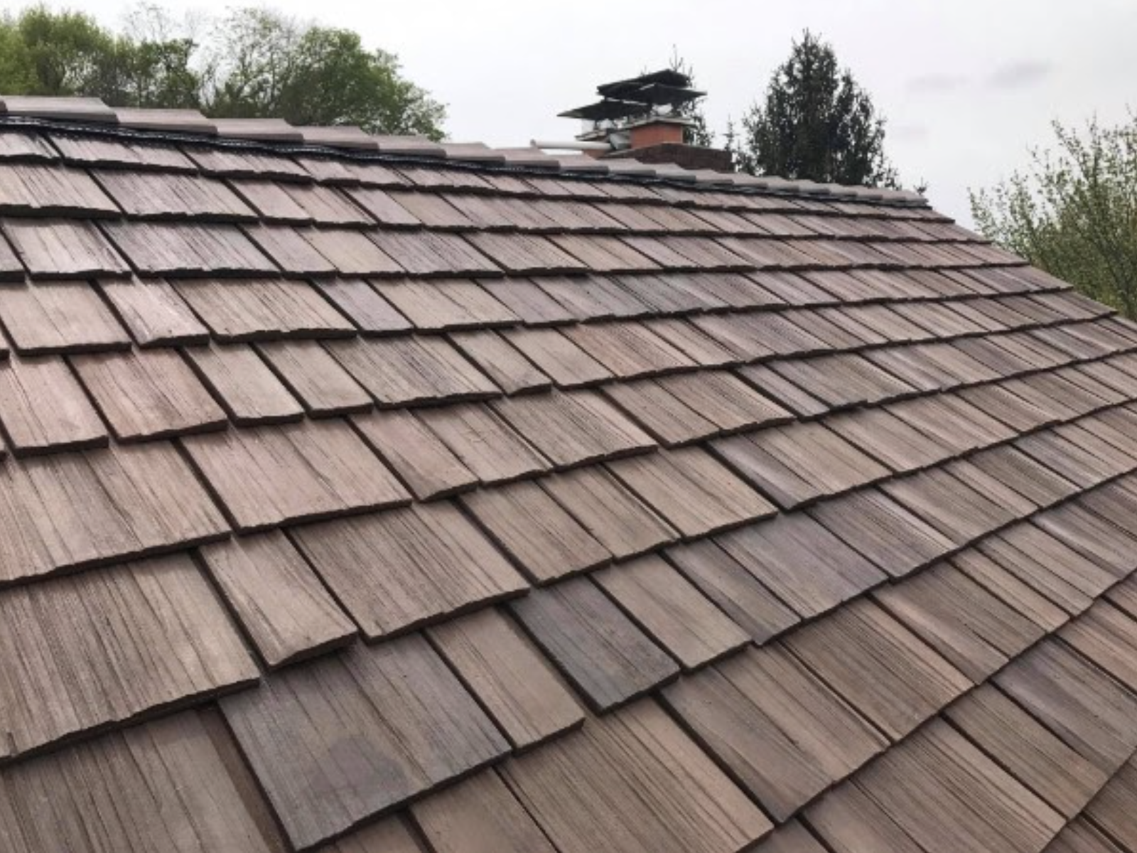 New cedar shake roof installed on upscale home with detailed rooflines
