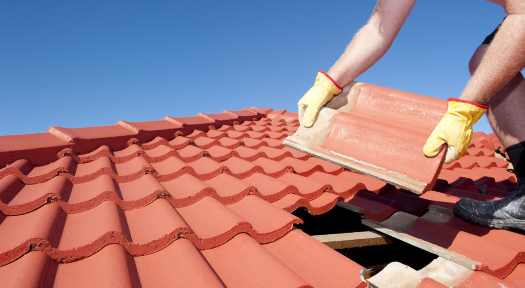 Experienced roofer inspecting flashing and shingle damage with specialized repair tools