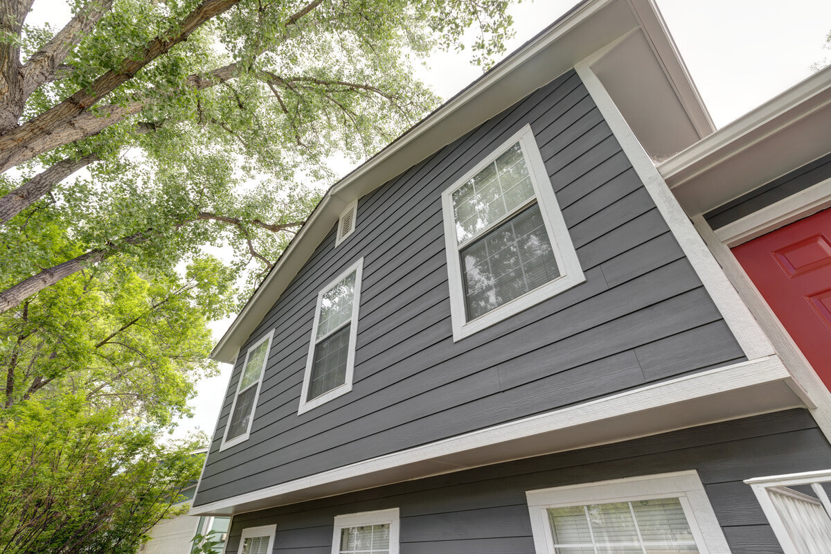 Skilled exterior technician inspecting damaged siding seams and moisture-prone wall sections